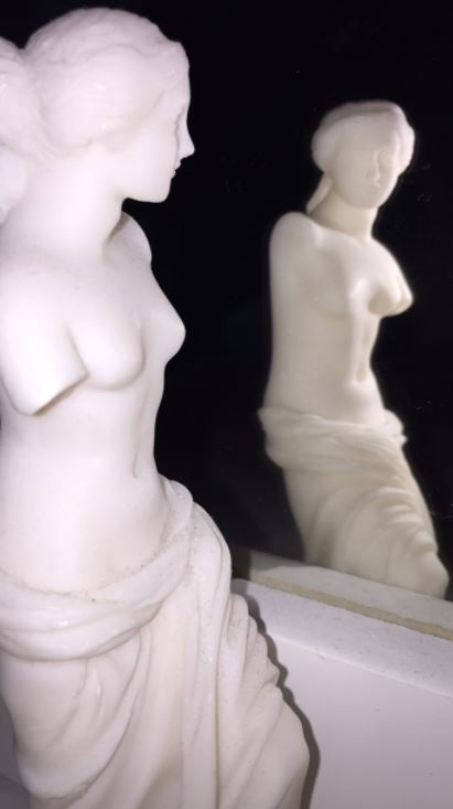 Aphrodite, the Greek Goddess of love and beauty, looks at her body’s reflection - the way that women reflect on their bodies to see if they conform to society’s views of beauty. 